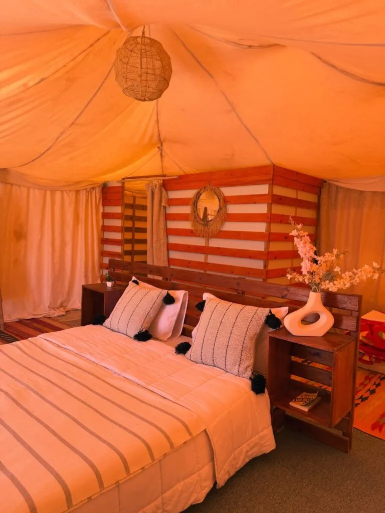 Tent interior glowing in warm light with striped bedding