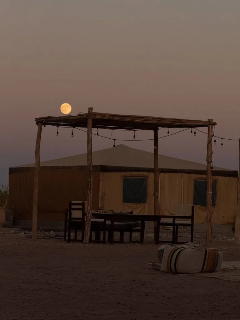 Full moon rising above a nomad tent and wooden pergola